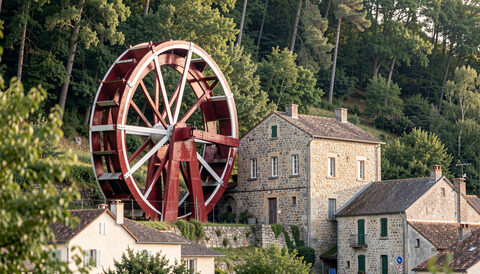 The Great Laxey Wheel, a huge red and white water wheel on a wooded hillside above a village.